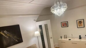A living room with a beige sofa, a chandelier, a white cabinet, and a door. - Stunning 2-bed Pet Friendly Apartment in Gateshead (Gateshead)