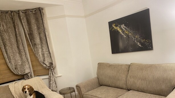 A living room with a beige sofa, a small round table, a dog under a blanket, and a black abstract painting on the wall. - Stunning 2-bed Pet Friendly Apartment in Gateshead (Gateshead)