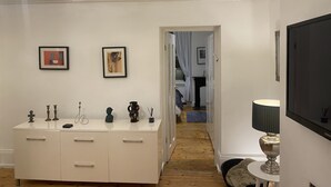 A hallway with a white dresser, framed artwork, a television, and a lamp. - Stunning 2-bed Pet Friendly Apartment in Gateshead (Gateshead)