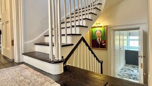 Un escalier avec une main courante noire et des balustres blanches, menant à l’étage supérieur.