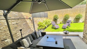 Une terrasse extérieure dotée d’un espace salon couvert, d’une table et de fauteuils.