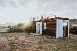 A small cabin with a wooden exterior, a balcony, and a door. - New! Endless Sunsets-Container Home (Alpine)