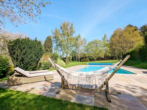 Un'amaca, una sedia a sdraio e una piscina in un giardino.