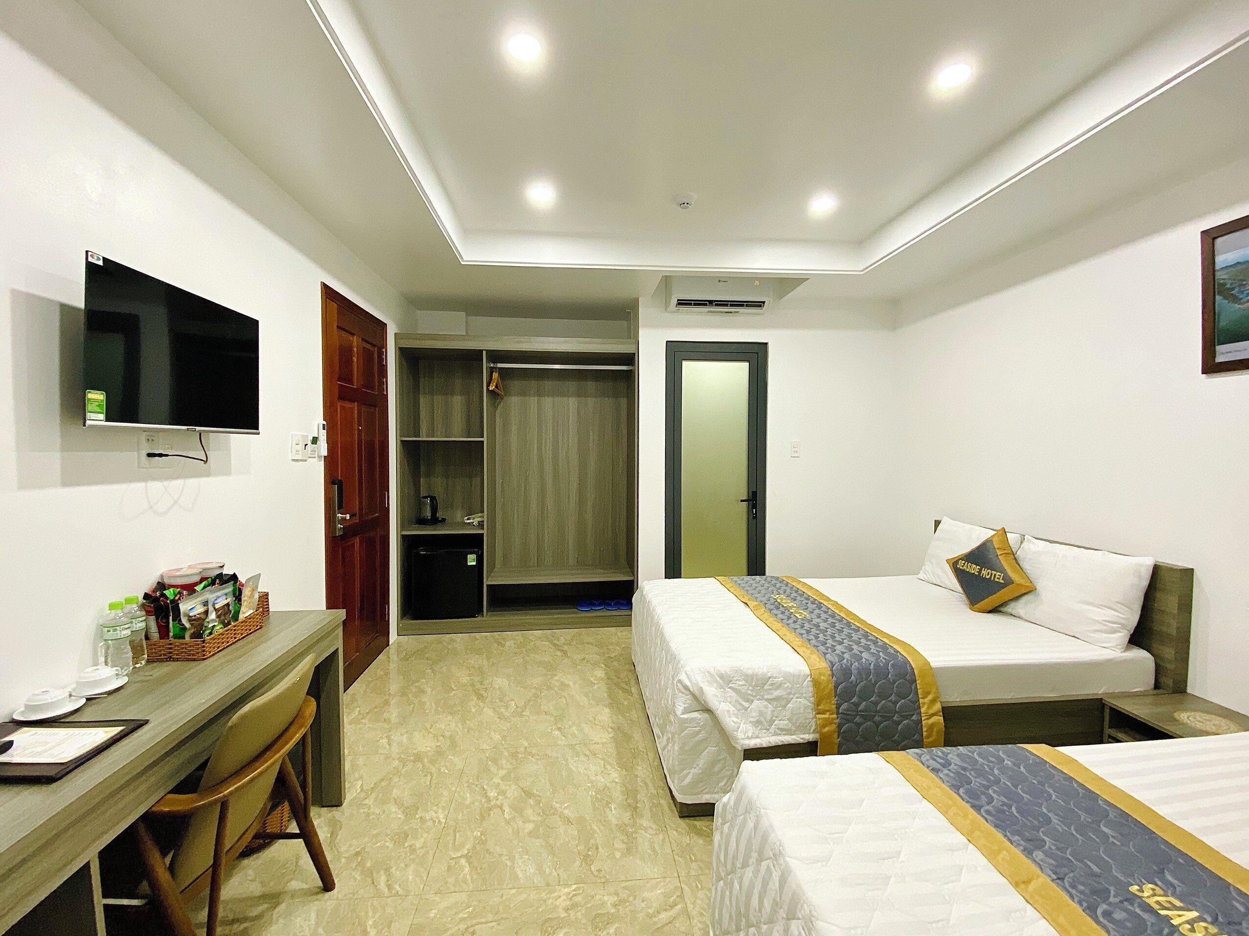 A hotel room with two beds, a desk, a television, and a wardrobe.