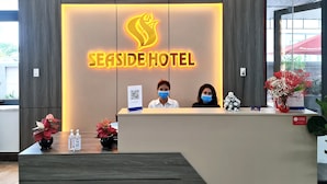 A reception desk at Seaside Hotel with a neon sign, clocks, and a view of the outside. - Seaside Hotel (Rach Gia)