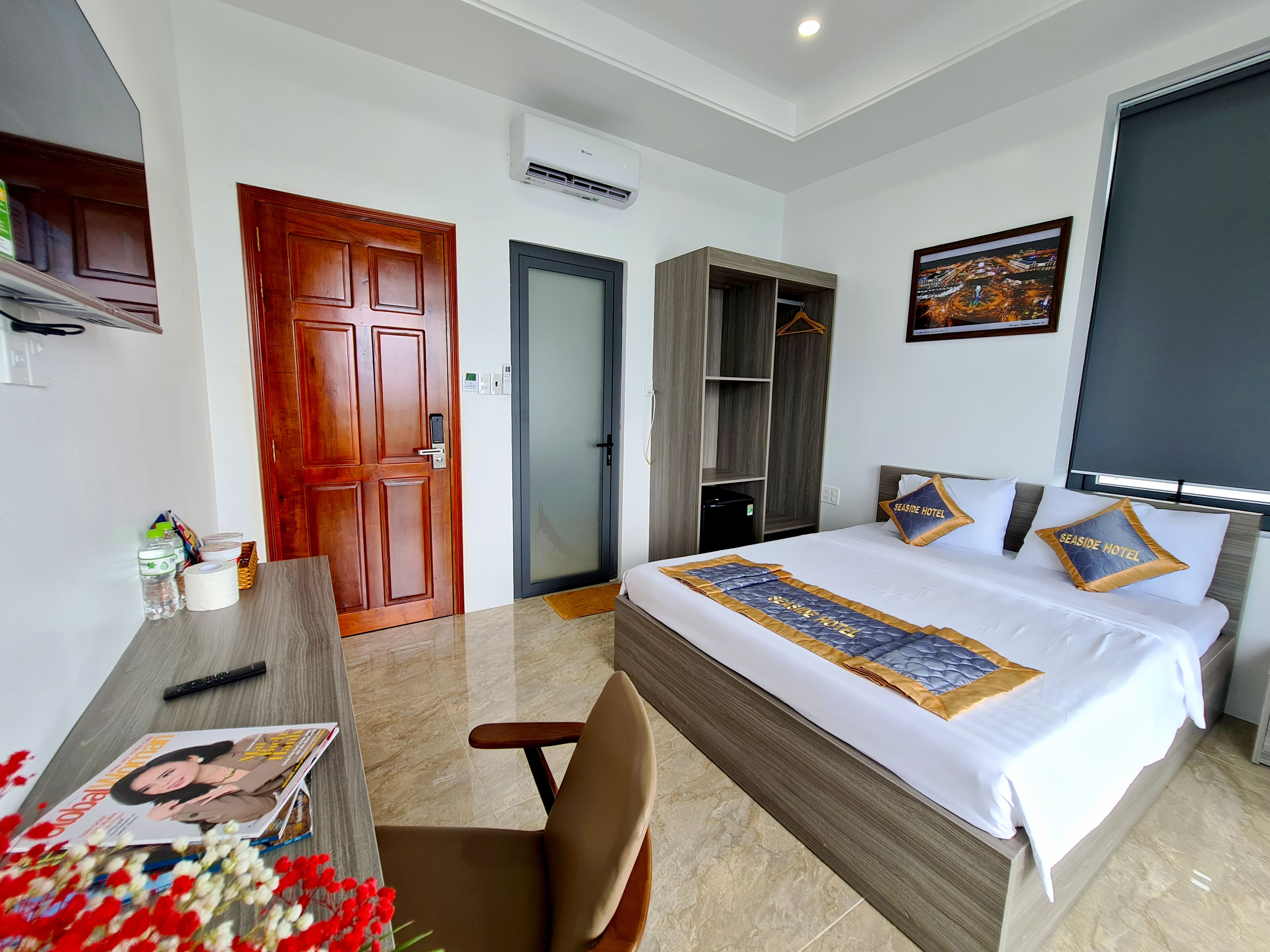 A hotel room with a bed, a desk, a wardrobe, and a door.