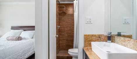 Une chambre d’hôtel avec un lit, une salle de bain avec une douche et un lavabo.