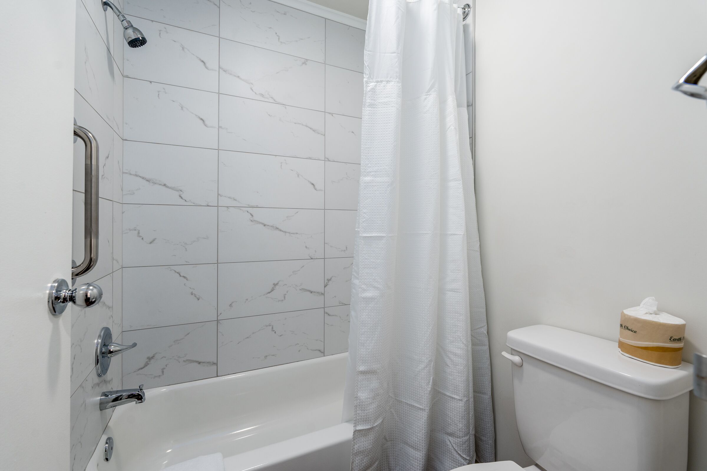 Une salle de bain avec une baignoire, des toilettes et un rideau de douche.