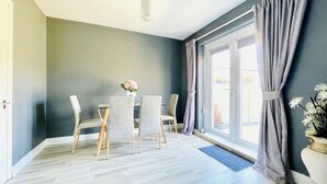Una habitación con una mesa de comedor y sillas, una ventana con cortinas, y una lámpara colgante.