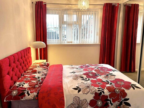 Classic hotel room with a large bed, floral-patterned bedspread, and a chandelier.