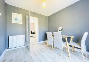Enjoy meals in a spacious dining area with a dining table and four chairs, a vase with flowers, and a radiator.