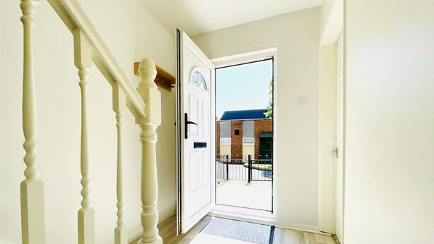 Un pasillo con una escalera de madera que conduce a una puerta.