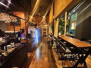 A cozy bar area with wooden flooring, bar stools, and a counter displaying various items. - FG Boutique Hostel (Sarajevo)