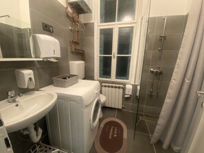 A modern bathroom with a washing machine, a sink, a toilet, and a shower. - FG Boutique Hostel (Sarajevo)