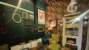 A cozy room with a fireplace, a bookshelf, and various framed pictures on the walls. - FG Boutique Hostel (Sarajevo)
