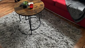 A living room with a red sofa, a round coffee table, a small table with a vase and wine glasses, and a floor lamp. - Inviting 1-bed Unit in Watford (Watford)