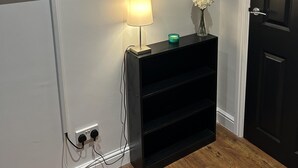 A hallway with a black console table, a wall-mounted TV, a mirror, and a door. - Inviting 1-bed Unit in Watford (Watford)