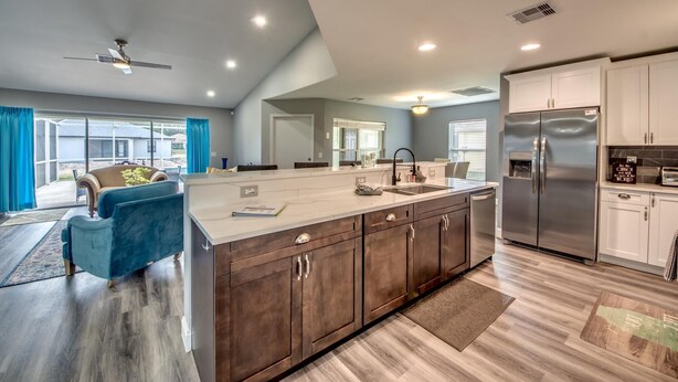 A modern kitchen with a large island, dark wood cabinets, stainless steel appliances, and a ceiling fan. - Villa Greene, Private Home, Elec. Heated Pool, WIFI, ..... (Cape Coral)