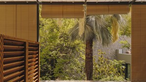A room with a view of a garden, a wooden bench, and a stone wall. - Hotel Palau Fugit (Girona)