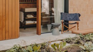 A wooden sliding door leading to a bathroom with a shower and a small seating area with a towel. - Hotel Palau Fugit (Girona)