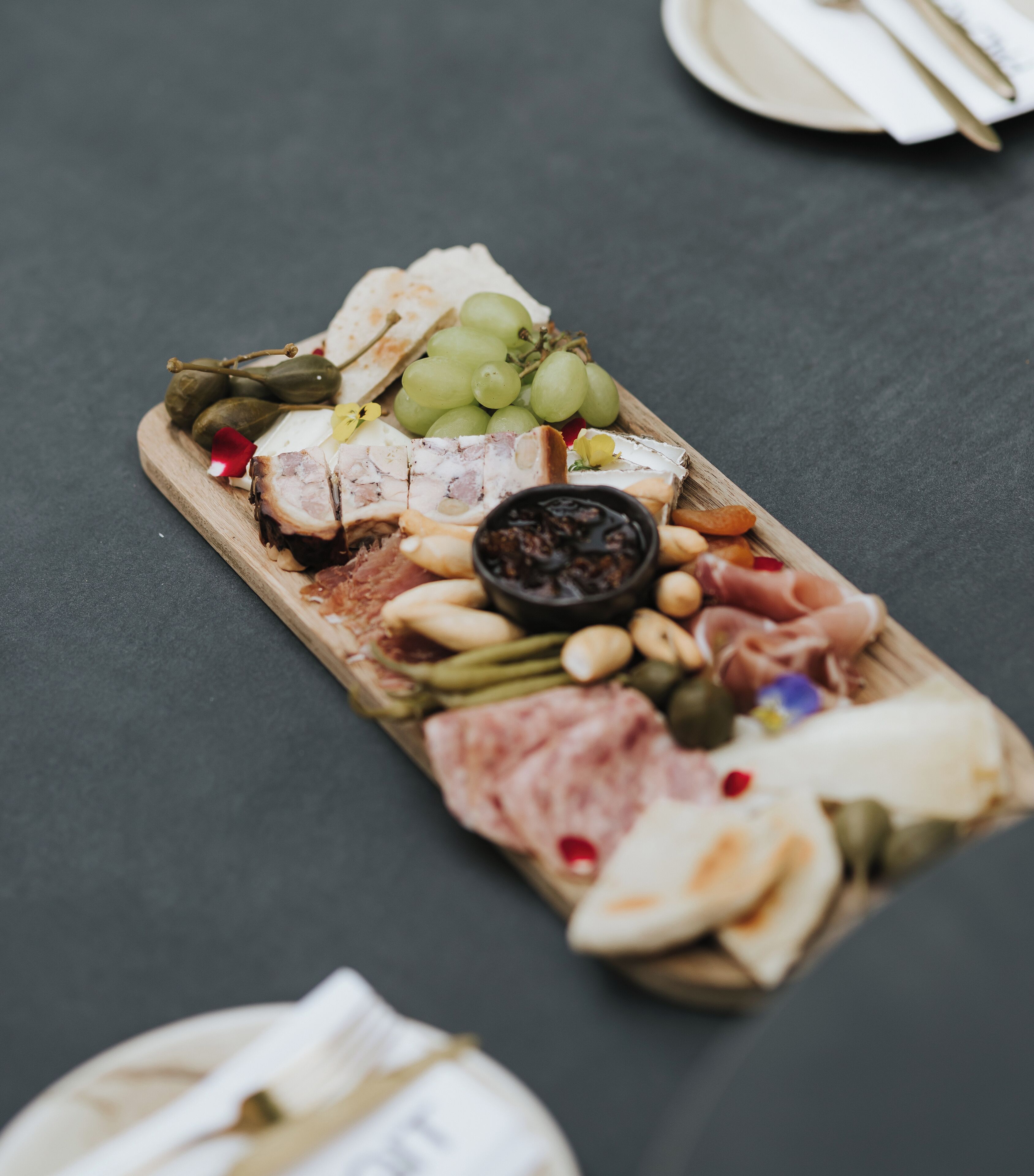 A charcuterie board with various meats, cheeses, fruits, and nuts on a wooden board.