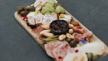 A charcuterie board with various meats, cheeses, fruits, and nuts on a wooden board.