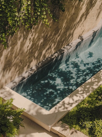Una piscina techada, una piscina al aire libre, sombrillas