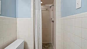 Un baño con ducha, inodoro y paredes de azulejos.
