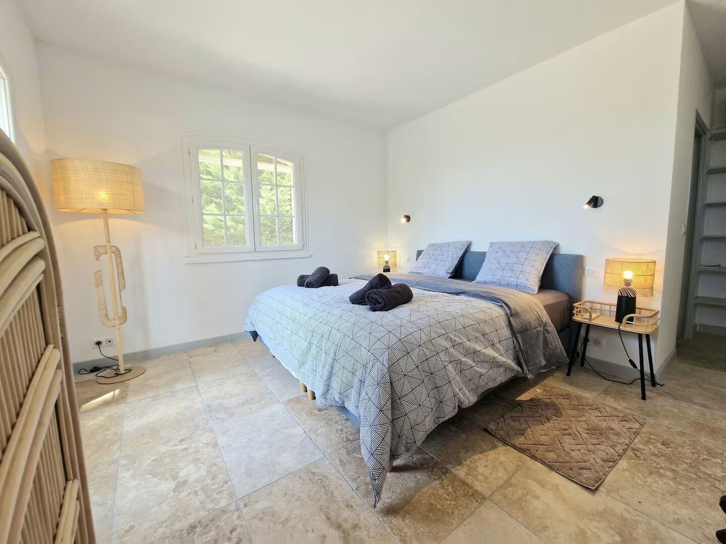 Une chambre à coucher avec un lit, deux lampes de chevet, une fenêtre et une lampe sur pied.