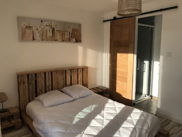 Un dormitorio con una cama de madera, una mesita de noche, una lámpara y un cuadro en la pared.