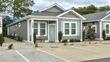 A row of single-story houses with a garage, a covered porch, and a small front yard with a chair and plants.