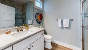 A bathroom with a white sink, a mirror, a toilet, and a shower area. - The Great Crabsby | Dogs OK! Walk to beach, Pool (Corolla)