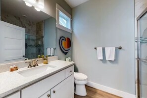 A bathroom with a white sink, a mirror, a toilet, and a shower area. - The Great Crabsby | Dogs OK! Walk to beach, Pool (Corolla)