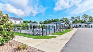 A residential area with a fenced pool, houses, and a clear sky.