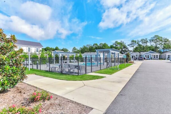 Un quartier résidentiel avec une piscine clôturée, des maisons et un ciel dégagé.