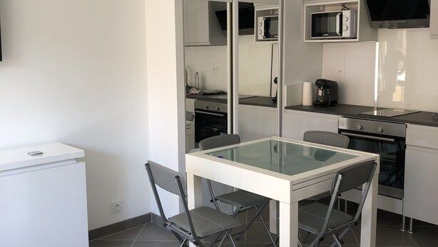 Eine moderne Küche mit Esstisch aus Glasplatte, einem weißen Kühlschrank und einer Mikrowelle.
