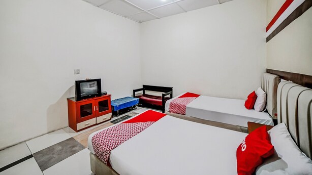 Ein Hotelzimmer mit zwei Betten, einem Fernseher auf einer Kommode und einer rot-weiß gestreiften Wand.