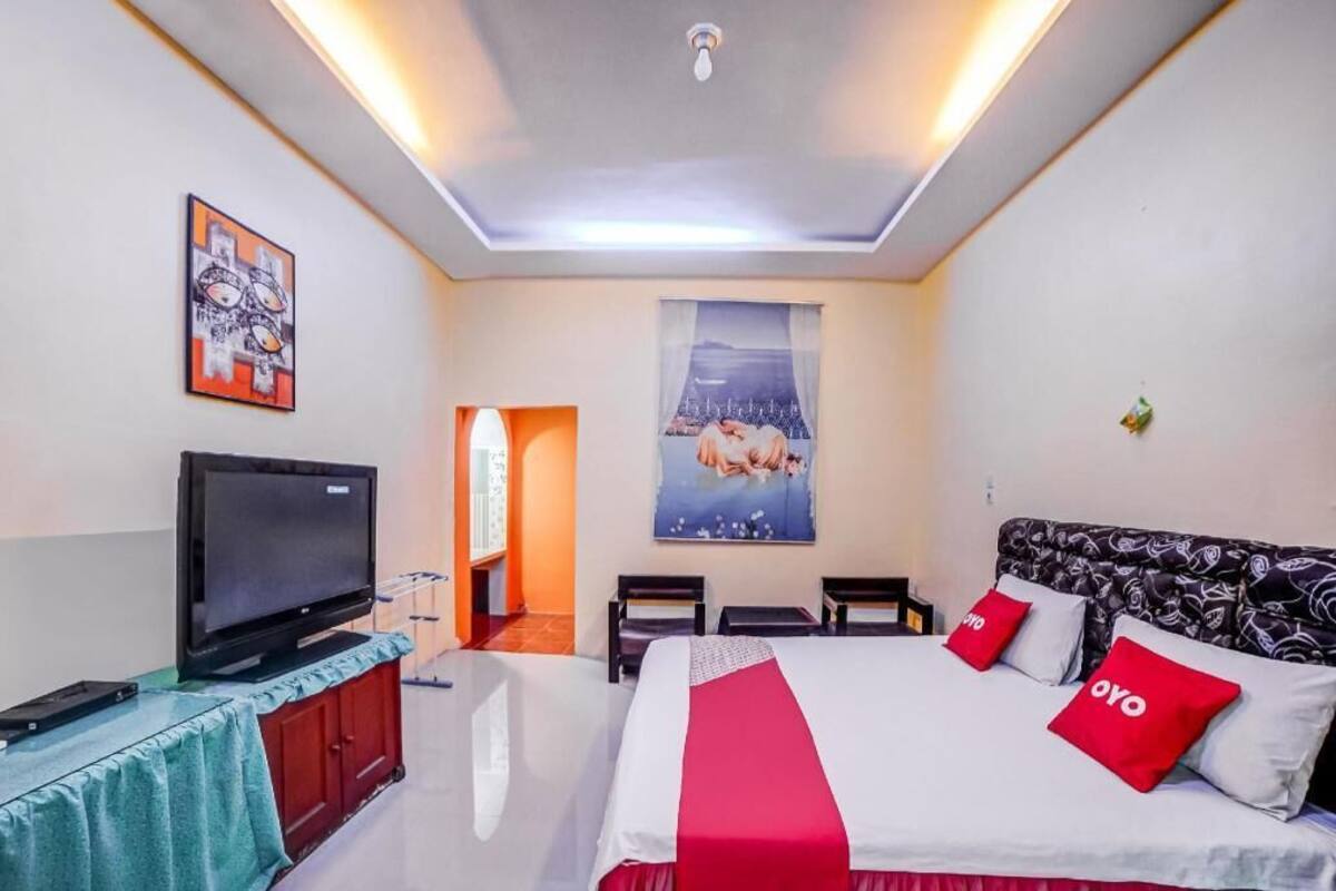 Ein Hotelzimmer mit einem Bett, einem Fernseher, einem Poster an der Wand und einer Tür zu einem anderen Raum.