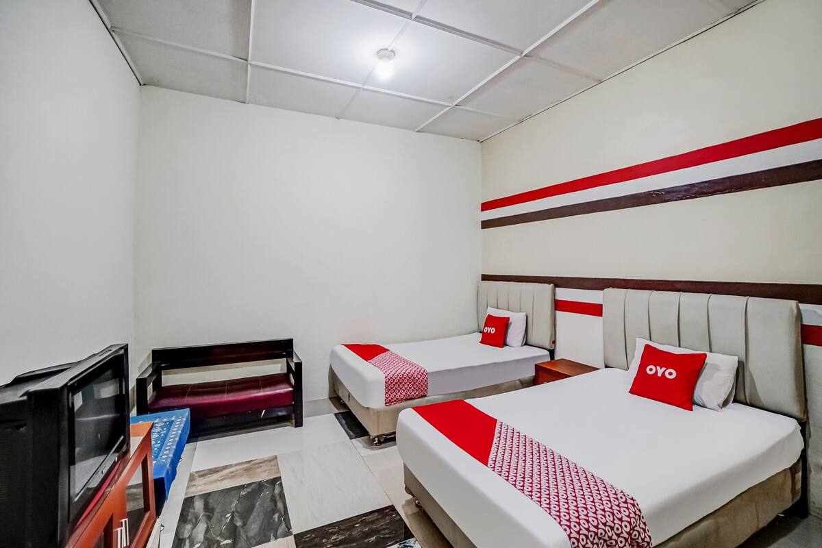 Ein Hotelzimmer mit zwei Betten, einem Fernseher und einem Schreibtisch.