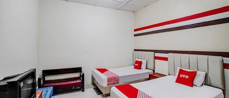 A hotel room with two beds, a TV, and a desk.