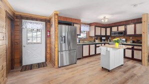 A wooden cabin-style kitchen with a refrigerator, microwave, and wooden cabinets.