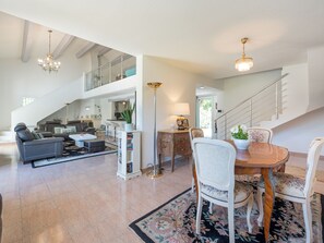 Cozy living area with a sofa, dining table, and staircase leading to an upper level.