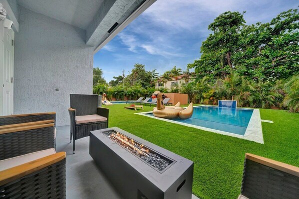 A backyard with a swimming pool, artificial flamingo float, and outdoor seating area.