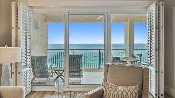 A balcony with a view of the ocean, furnished with chairs and a table. - HP 45W What the Heck @ High Pointe | Lagoon Pool | Tennis & Pickleball Courts (High Pointe Resort)