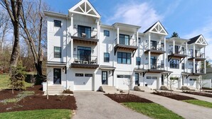 Un immeuble résidentiel moderne à plusieurs étages, doté d’une façade symétrique, de nombreux balcons et d’une entrée centrale.