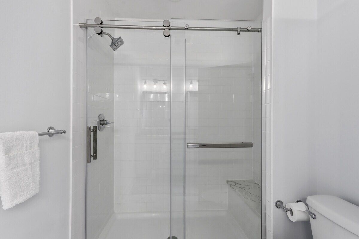 A modern bathroom with a glass-enclosed shower, a toilet, and a towel rack.