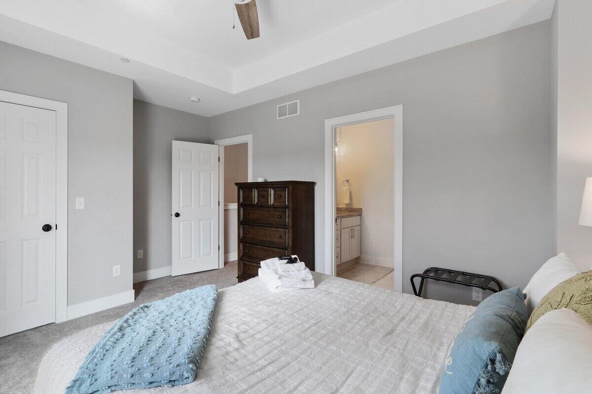 A bedroom with a large bed, a dresser, and a walk-in closet.