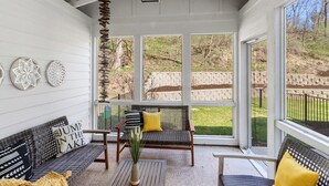 Un patio couvert avec deux canapés en osier, une petite table et des éléments décoratifs muraux.