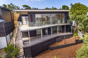 A modern two-story house with large glass windows, a balcony, and a wooden deck. - 28 Ennisvale Ave (Sandy Point)