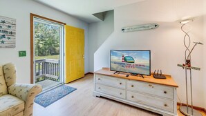 Ein Zimmer mit Fernseher, einem Holzschrank, einer gelben Tür und Blick ins Freie.